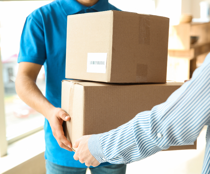 Person in blue shirt hands over packages to person in striped shirt. The image is meant to show the strain Black Friday puts on retail workers and why they'll benefit from retail supply chain solutions.