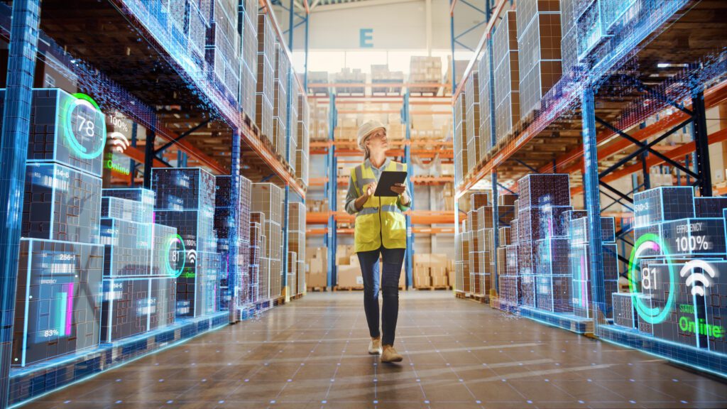 Woman walks through cargo and looks at digitized information, showing how supply chain technology is the future of supply chain management.