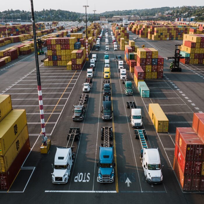 Several trucks and cargo in a lot. They're meant to represent how coordination of multiple companies and data is integral to the future of logistics.