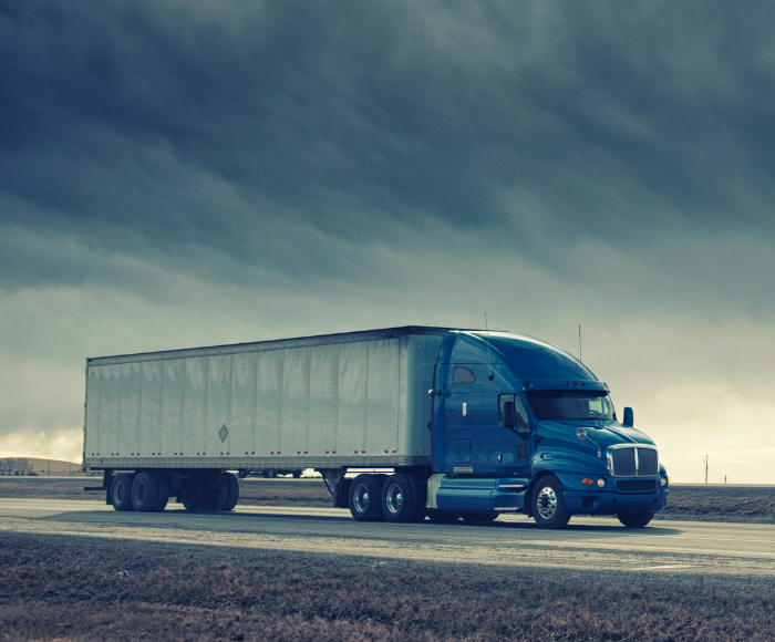 Blue truck drives through a storm, showing climate change's impact on supply chains.