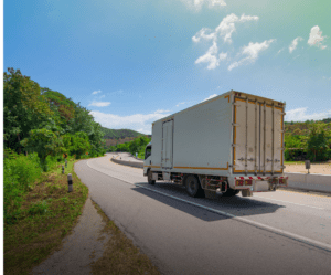 Image of truck on road during the day, as seen from the back.